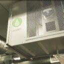 Déshumidificateur Anden fixé au mur, avec conduits et tuyaux métalliques visibles dans un environnement industriel bien éclairé.