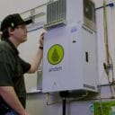 Technician inspecting an Anden dehumidifier unit with a prominent green logo in a well-lit utility room.