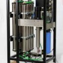 Industrial water filtration system with stainless steel tubes, a motor, and various valves, mounted on a wooden pallet.