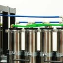 Four stainless steel filters connected by colorful tubing, with a control panel visible on the left side.