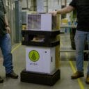 Two individuals stand beside a stacked Anden unit, showcasing its design in a warehouse setting with equipment in the background.