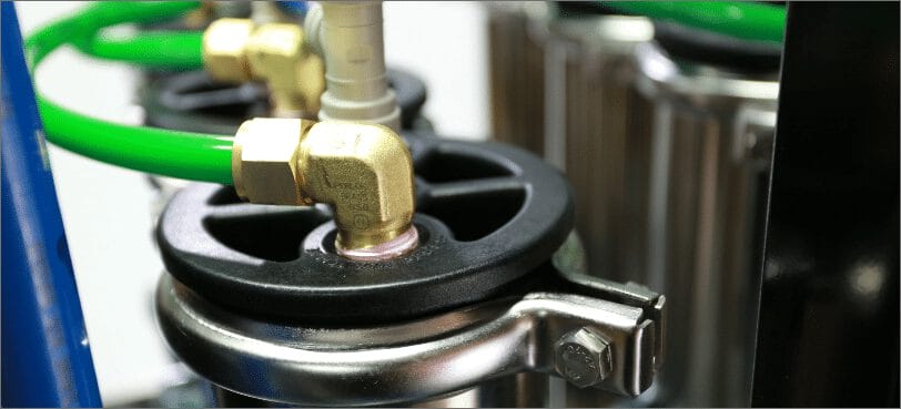 Gros plan sur les connecteurs métalliques et les tubes verts d'un système de filtration, montrant les détails de l'assemblage et des matériaux.