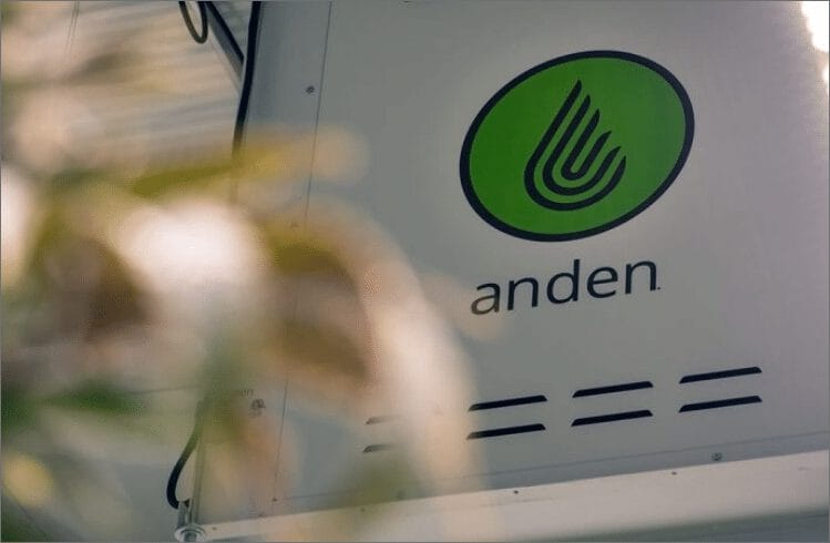 Logo vert avec un motif de feuille stylisé et le mot « anden » affiché sur un fond blanc, partiellement masqué par du feuillage.