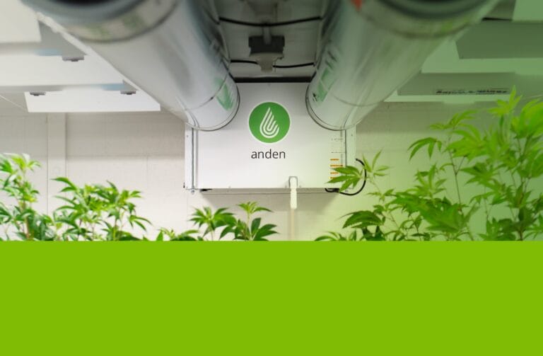 Ventilation system labeled "anden" mounted on a wall, surrounded by green plants in a well-lit indoor setting.